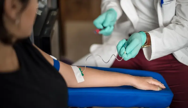 Γιατρός συλλέγει δείγμα αίματος από ασθενή με τη χρήση σύριγγας.