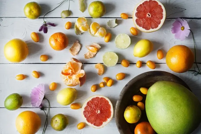 A variety of fresh fruits, including citrus and tropical options, arranged on a wooden surface, showcasing vibrant colors and natural health benefits.