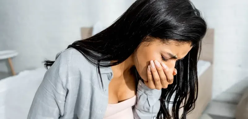 Έγκυος γυναίκα που κρατά την κοιλιά της και φαίνεται να νιώθει ναυτία.