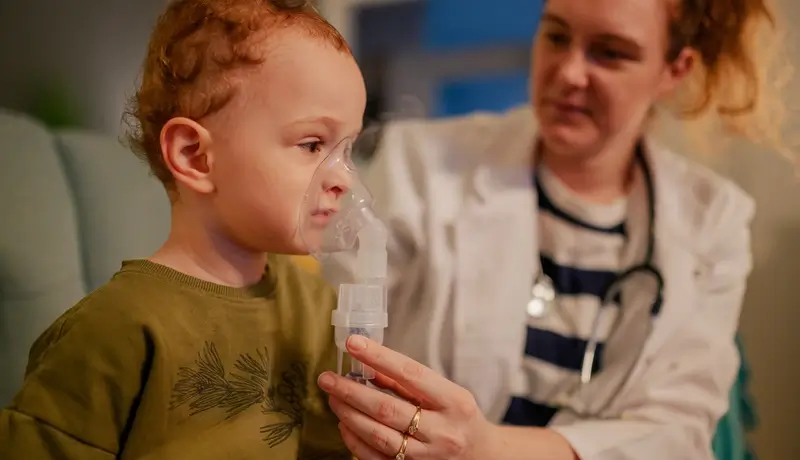 Παιδί που χρησιμοποιεί νεφελοποιητή με μάσκα οξυγόνου, υπό την επίβλεψη γιατρού.