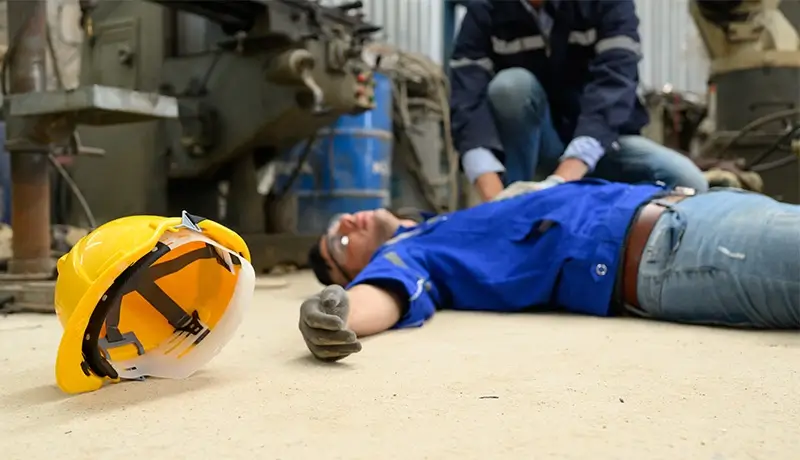 A male worker having collapsed with a colleague trying to help him