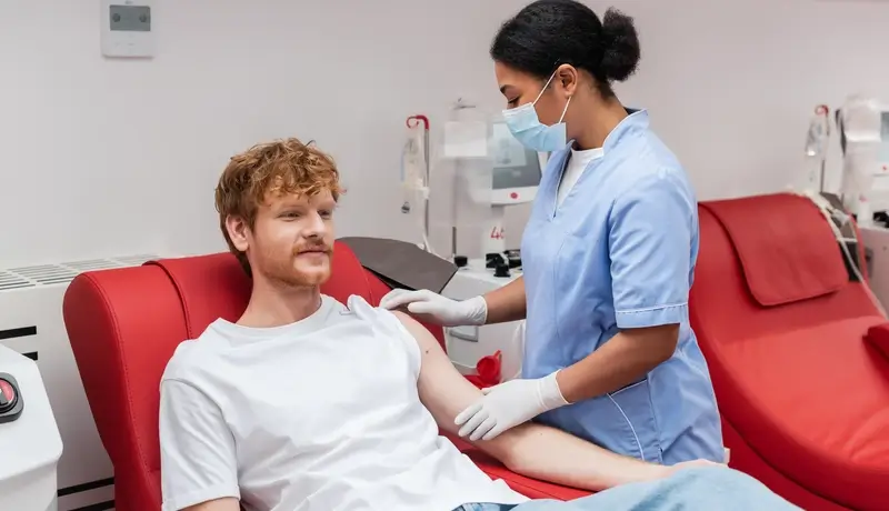 Ναυτικός λαμβάνει φροντίδα από νοσοκόμα κατά τη διάρκεια αιμοδοσίας σε ιατρικό κέντρο.