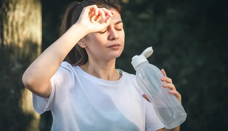 Attractive young woman drinks water after jogging in the park.