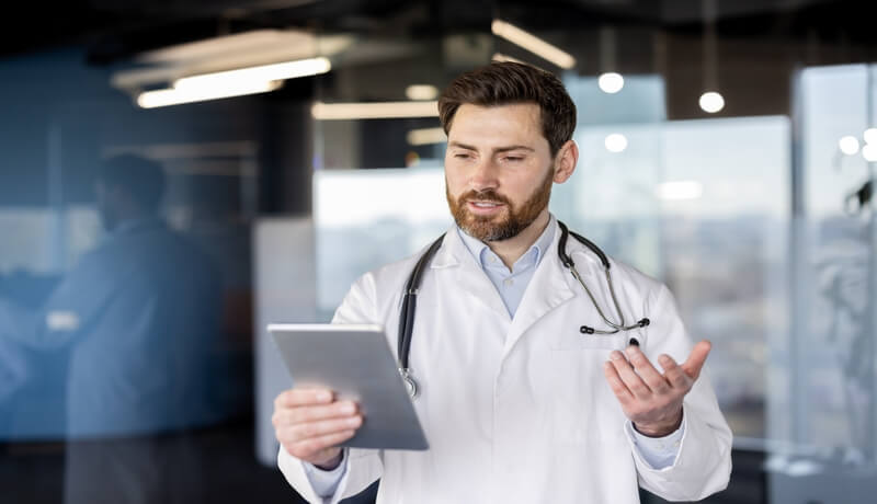 Γιατρός που χρησιμοποιεί tablet για τηλεϊατρική συνεδρία σε σύγχρονο ιατρείο.
