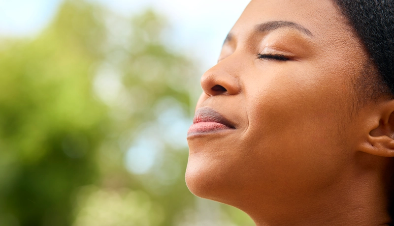  Γυναίκα που απολαμβάνει τη φρέσκια ατμόσφαιρα με κλειστά μάτια, εστιάζοντας στην αναπνοή της.