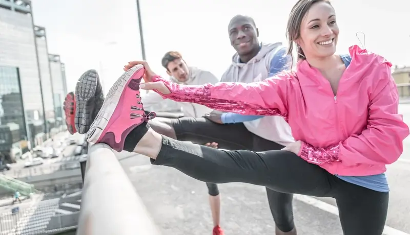 Άνθρωποι που κάνουν διατάσεις πριν την άσκηση, τεντώνοντας τα πόδια τους για προθέρμανση.