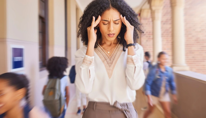 Μια γυναίκα με έντονη δυσφορία κρατά το κεφάλι της με τα χέρια της, υποφέροντας από ίλιγγο ή πονοκέφαλο σε πολυσύχναστο χώρο.