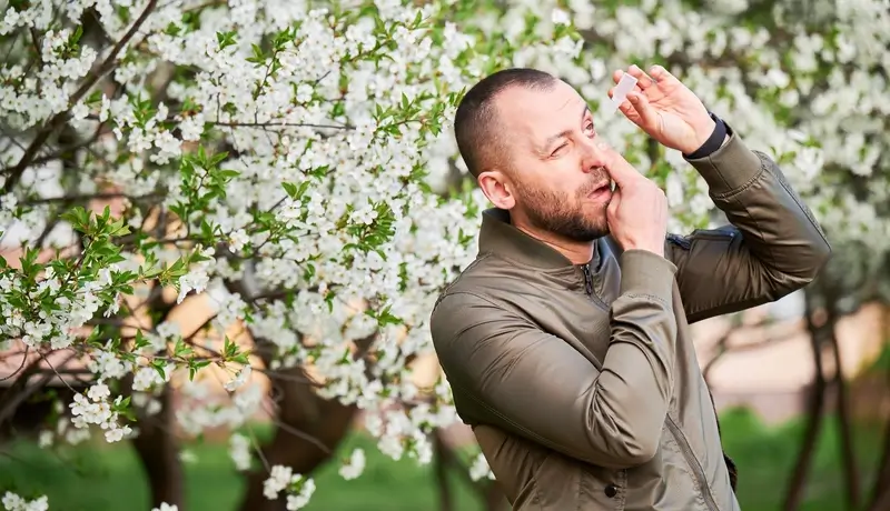 A man using medical eye drop, suffering from seasonal allergy