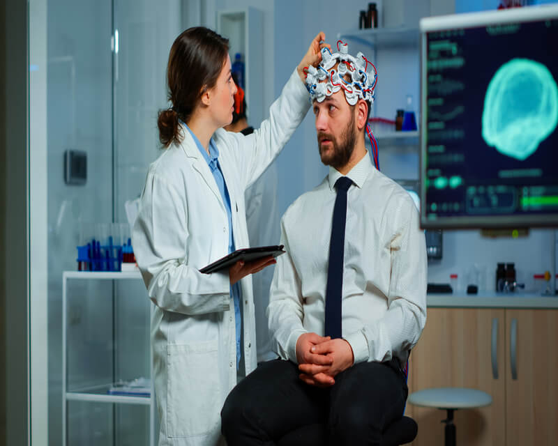 Man sitting on neurological chair with brainwave scanning headset