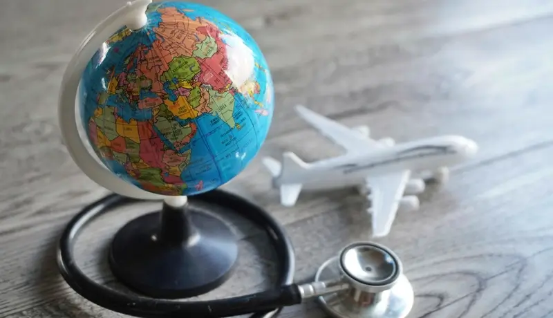 Globe, airplane, and stethoscope symbolizing medical care for tourists.