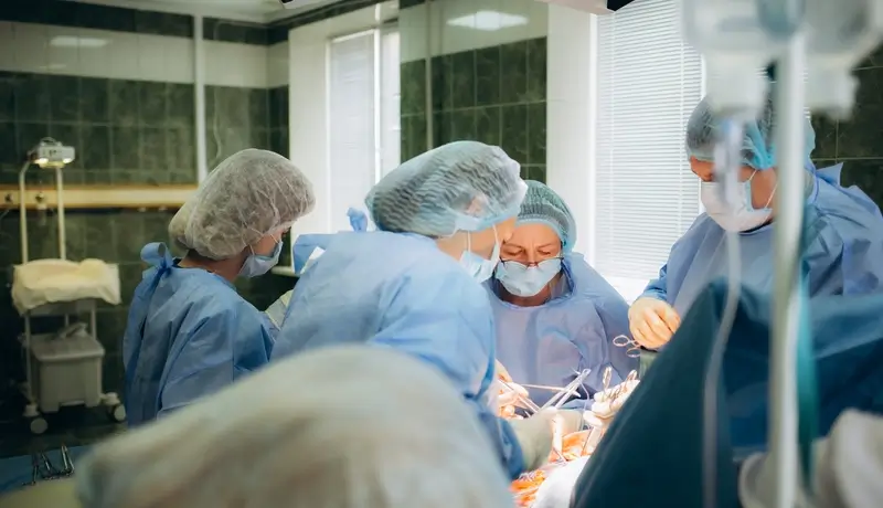 A team of doctors and nurses performing surgery in an operating room.