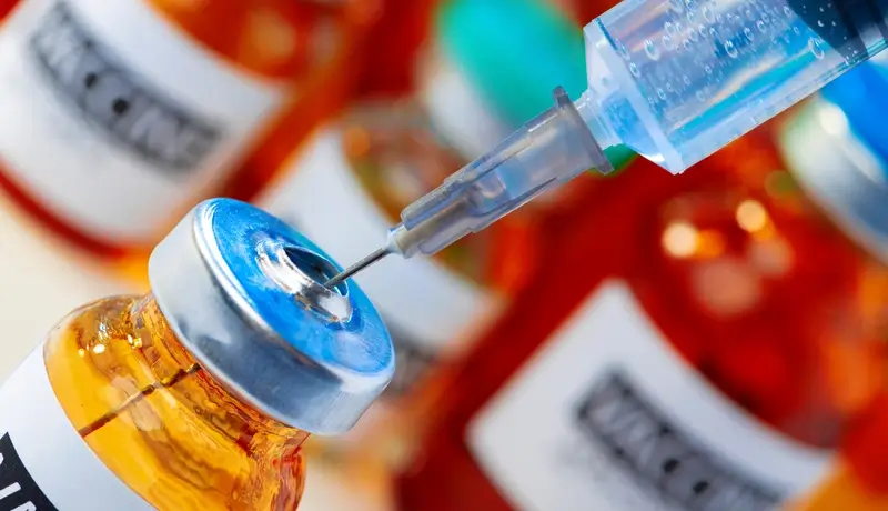  A syringe drawing liquid from a vaccine vial, representing the role of vaccines and precision therapy in oncology.