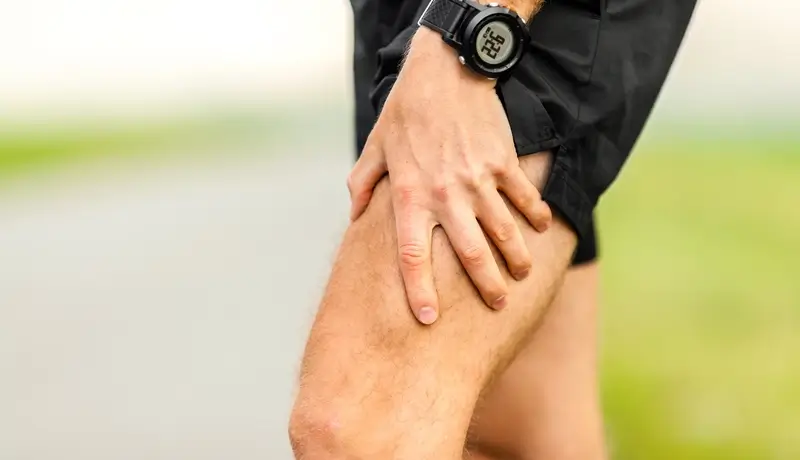 Άντρας που κρατά το μπροστινό μέρος του μηρού του, δείχνοντας σημάδια μυϊκού πόνου στο πόδι του.