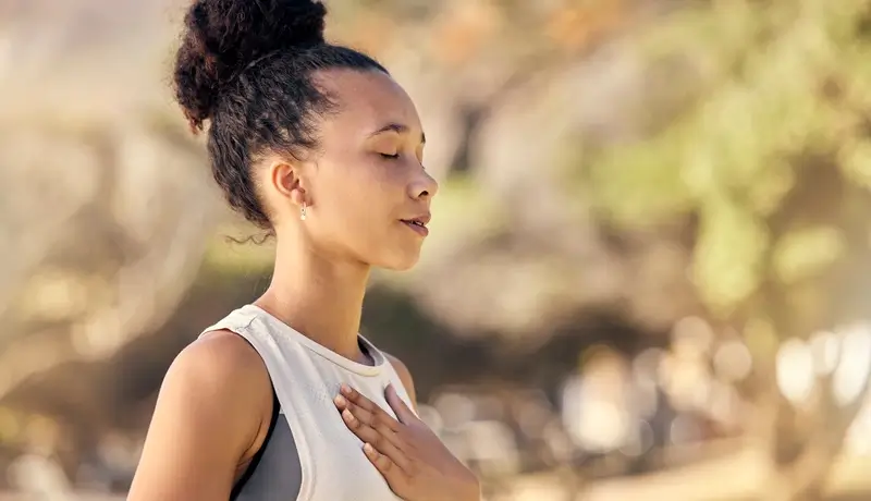  Γυναίκα με κλειστά μάτια αναπνέει βαθιά σε εξωτερικό χώρο.