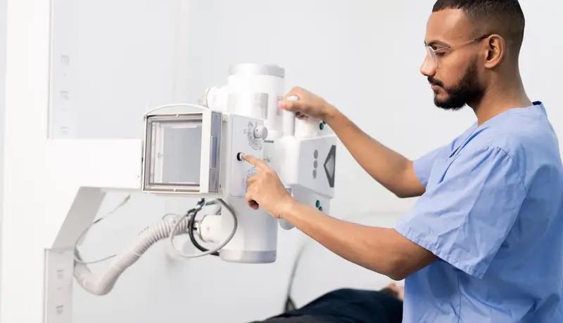Healthcare professional operating an X-ray machine during a medical examination.